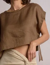 Blusa corta de lino Elan, de corte crop y silueta holgada, con hombros caídos, escote a la base y lazos ajustables en los laterales.