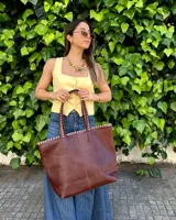 Bolso grande de cuero marrón, tipo shopper, con costuras artesanales decorativas en contraste a lo largo del borde superior y las asas de hombro.
