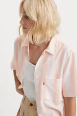 Camisa de manga corta Levi's con diseño de rayas verticales en tonos blanco y durazno. Presenta cuello clásico, cierre frontal con botones y un bolsillo en el pecho con la etiqueta roja característica de la marca.