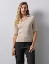 Buzo azul de tejido acanalado, con cuello solapa y escote en V en tejido calado.