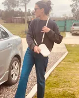 Cartera pequeña negra con diseño acolchado, cierre de cremallera y correa de mano. Incluye tarjetero interno.