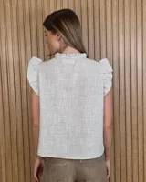 Musculosa a rayas verdes y blancas, con cuello alto fruncido, cierre frontal con botones y volados en los hombros.