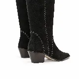 Bota alta de gamuza negra con caña alta, punta afinada, taco bajo ancho y costuras decorativas artesanales a lo largo de la silueta. Cuenta con cierre lateral.