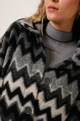 Tapado largo de lana con estampado zigzag horizontal en tonos grises y negros, de manga larga y abotonado.