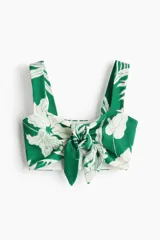 Cropped top de punto con textura, diseño ajustado, breteles anchos y nudo decorativo en el centro del busto. Prenda forrada con estampado botánico.
