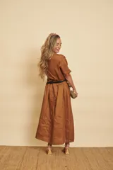 Vestido tipo túnica largo de lino, color bordo, con mangas cortas, bolsillos laterales y detalle de volados en la botonera frontal.