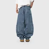 Pantalón de jean estilo cargo con corte ultra baggy y diseño de paneles. Presenta bolsillos laterales tipo cargo con bordes deshilachados y costuras reforzadas. Confeccionado en denim de algodón con textura rústica.