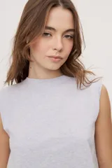 Remera sin mangas negra con cuello redondo y hombros estructurados con hombreras, de corte recto y largo a la cintura.