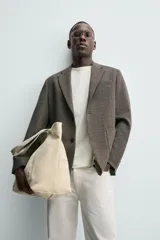 Blazer regular fit confeccionado en mezcla de lana y lino, con diseño de pata de gallo en tonos marrones y grises. Cuenta con cuello de solapas de muesca, cierre frontal de dos botones, bolsillos de plastrón en la cadera y bolsillo de vivo en el pecho.