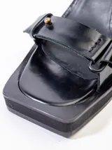Sandalias negras de cuero vacuno con tiras, detalles de gemelos en bronce, taco de madera y plataforma de EVA.