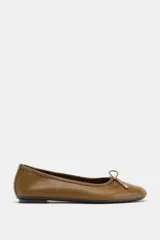 Zapato tipo bailarina de cuero color marrón, con punta redonda y detalle de lazo decorativo con herraje metálico en la parte delantera.