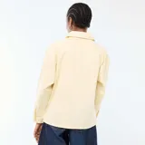 Chaqueta vaquera color amarillo claro, de corte recto y largo medio, con cuello camisero, cierre frontal de botones y dos bolsillos delanteros de parche.
