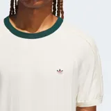 Camiseta Adidas Originals de corte holgado, color blanco con cuello redondo acanalado en color verde oscuro. Presenta un diseño sutilmente texturizado y el logo del trébol bordado en el pecho.