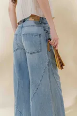 Pantalón de jean color beige, de tiro medio, corte amplio y ruedo acampanado.