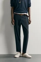 Pantalón chino negro slim fit de corte recto, con bolsillos frontales, trabillas para cinturón y cierre frontal con cremallera y botón.
