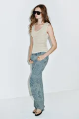 Jeans de tiro alto con corte flare y diseño de tejido jacquard con patrón floral. Presenta cinco bolsillos, trabillas en la cintura y cierre frontal con cremallera y botón.