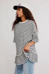Remera oversize de punto rayada en blanco y negro, con cuello redondo, mangas cortas amplias y detalle de volado fruncido en el ruedo.