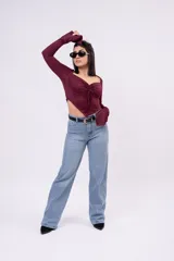 Crop top de manga larga color bordó, confeccionado en tela elastizada. Presenta escote corazón, frunce ajustable con cordón en el centro del pecho y dobladillo inferior en pico. Las mangas largas cuentan con detalle acampanado en los puños.