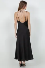 Vestido largo tipo slip dress confeccionado en tela satinada color negro, con escote en V y breteles finos.