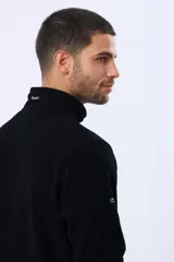 Buzo de abrigo de polar color negro, con cuello alto, medio cierre metálico frontal y bolsillos laterales con cierre. Presenta logo a tono bordado en el pecho.