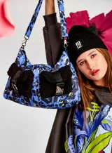 Bolso puffer chico capitoneado con estampado animal print en tonos azul y negro, con bolsillos de sherpa negros y correa desmontable con estampado a juego.