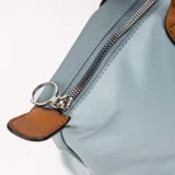 Bolso tipo tote bag color gris azulado con detalles en marrón. Tiene doble asa de hombro marrón, cierre superior y bolsillo frontal con cierre.