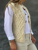 Chaleco tejido en lana merino con diseño de rombos en relieve, cierre frontal con botones de guampa y detalles en cuero.