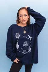 Buzo de cuello redondo y manga larga en color azul marino, con diseño estampado en blanco que representa el mapa de Uruguay junto a íconos culturales como el sol, el mate, el escudo nacional y un hornero.