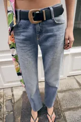 Jeans de tiro medio con corte slim fit, confeccionados en denim azul clásico. Presentan diseño de cinco bolsillos, cierre frontal con cremallera y botón, e incluyen un cinturón negro con hebilla metálica.