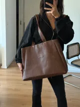 Bolso tipo tote grande confeccionado en cuero vacuno color marrón, con cierre superior, bolsillo interno y gancho para llaves.