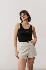 Short gris claro de tiro alto con costuras pespunteadas en contraste y bolsillos traseros amplios. Presenta una etiqueta de cuero rojo en la parte posterior de la cintura.