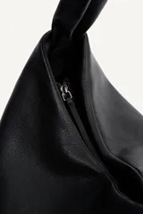 Bolso tipo shopper de hombro confeccionado en piel de alta calidad, con diseño minimalista y cierre principal mediante cremallera. Cuenta con un bolsillo interior con cierre y asa ajustable.