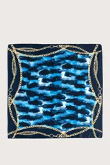 Pañuelo cuadrado de tela ligera con estampado abstracto en tonos azules y negros, enmarcado por un diseño de cadenas doradas.