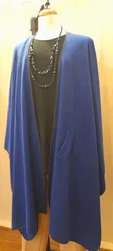 Ruana larga azul royal de paño con presilla y vivo negro en el borde.