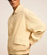 Campera masculina de ana ruga texturizada en color beige, con cuello inglés, cierre frontal por cremallera, bolsillos frontales con solapa, puños y cintura elásticos.