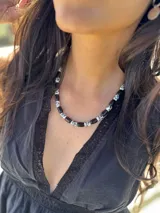 Collar corto con cuentas cilíndricas de cerámica negra con estampado floral blanco y cuentas de piedra reconstituida.