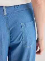 Pantalón jean celeste de corte ancho, con ruedo combinado en un tono más claro.