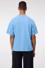 Remera de algodón celeste de corte relajado, con cuello redondo ribeteado y mangas cortas con hombros caídos.