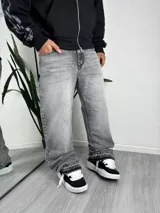 Pantalón jean de corte ancho y estilo acampanado, color gris con efecto acid wash y sutiles tonos verdosos.