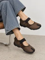 Zapatos tipo Mary Jane color marrón de cuero, con diseño de punta dividida estilo tabi, tira elástica con cierre ajustable sobre el empeine y suela de goma negra.