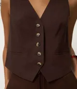 Chaleco femenino confeccionado en viscolino celeste, con escote en v, cierre por botones contrastantes y bolsillos delanteros.