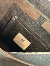Cartera tote Chabas modelo Molly, confeccionada en cuero genuino color marrón chocolate. Presenta diseño amplio con asas largas de hombro, costuras visibles, parche frontal con logo grabado y un pequeño monedero colgante removible con broche a presión.
