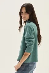 Polera de tejido de punto color azul, con cuello alto, manga larga y puños acanalados.