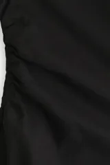 Top de manga larga en punto de algodón con cuello redondo, hombros caídos y detalle de frunces laterales que generan un bajo acampanado.