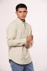Camisa de manga larga en color gris, confeccionada en algodón, con cuello abotonado y cierre frontal de botones.