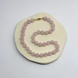Collar de cuentas esféricas de cuarzo rosa de 10 mm, unidas mediante nudos de hilo rosado. Presenta un cierre de mosquetón con baño de oro.