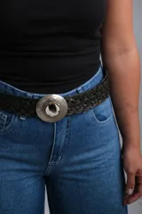 Cinto trenzado de cuero negro con hebilla circular metálica grabada y detalle central de piedra natural.