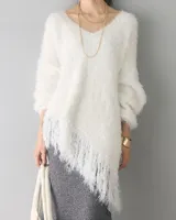 Sweater tipo poncho de punto peludo color blanco, con escote en V y flecos asimétricos en el dobladillo.