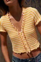 Top chaqueta de punto a rayas horizontales rojas y blancas, con escote pico, manga corta y volantes. Cierre frontal con botones.