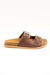Sandalias de cuero marrón, con dos tiras anchas ajustables mediante hebillas metálicas doradas. Cuenta con una suela de corcho y base dentada.